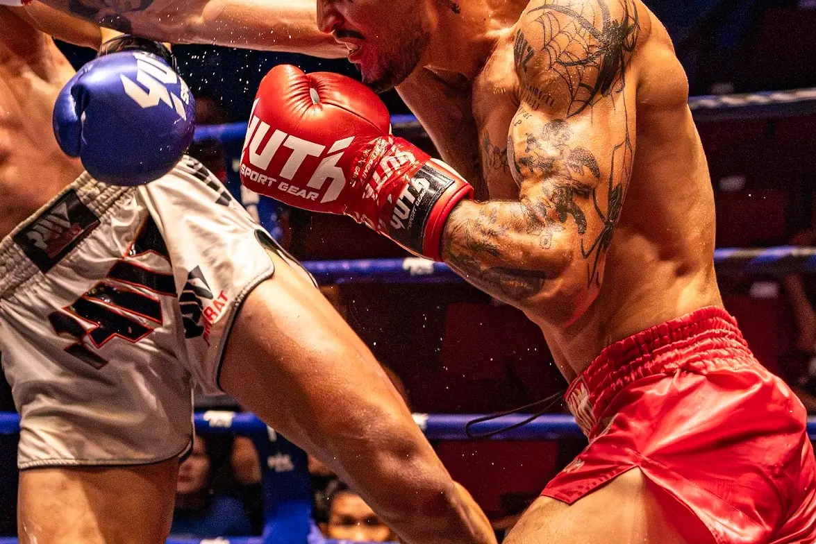 Two fighters exchange a punch and a kick at close range